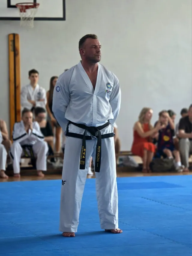 Piotr Kaczka w stroju taekwondo z czarnym pasem